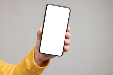 Photo of Man showing smartphone on grey background, closeup. Mockup for design