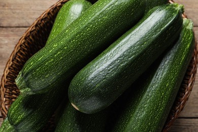 Photo of Raw ripe zucchinis in wicker basket on table, top view