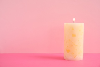 Alight wax candle on color background. Space for text