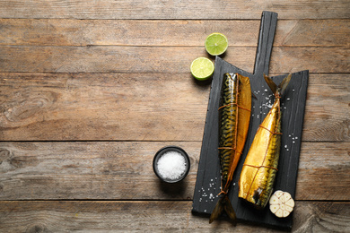 Photo of Tasty smoked fish on wooden table, flat lay. Space for text