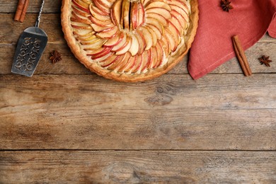 Flat lay composition with delicious homemade apple tart on wooden table. Space for text