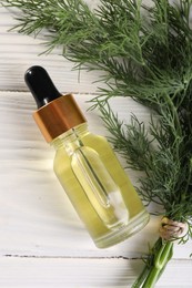 Bottle of essential oil and fresh dill on white wooden table, flat lay