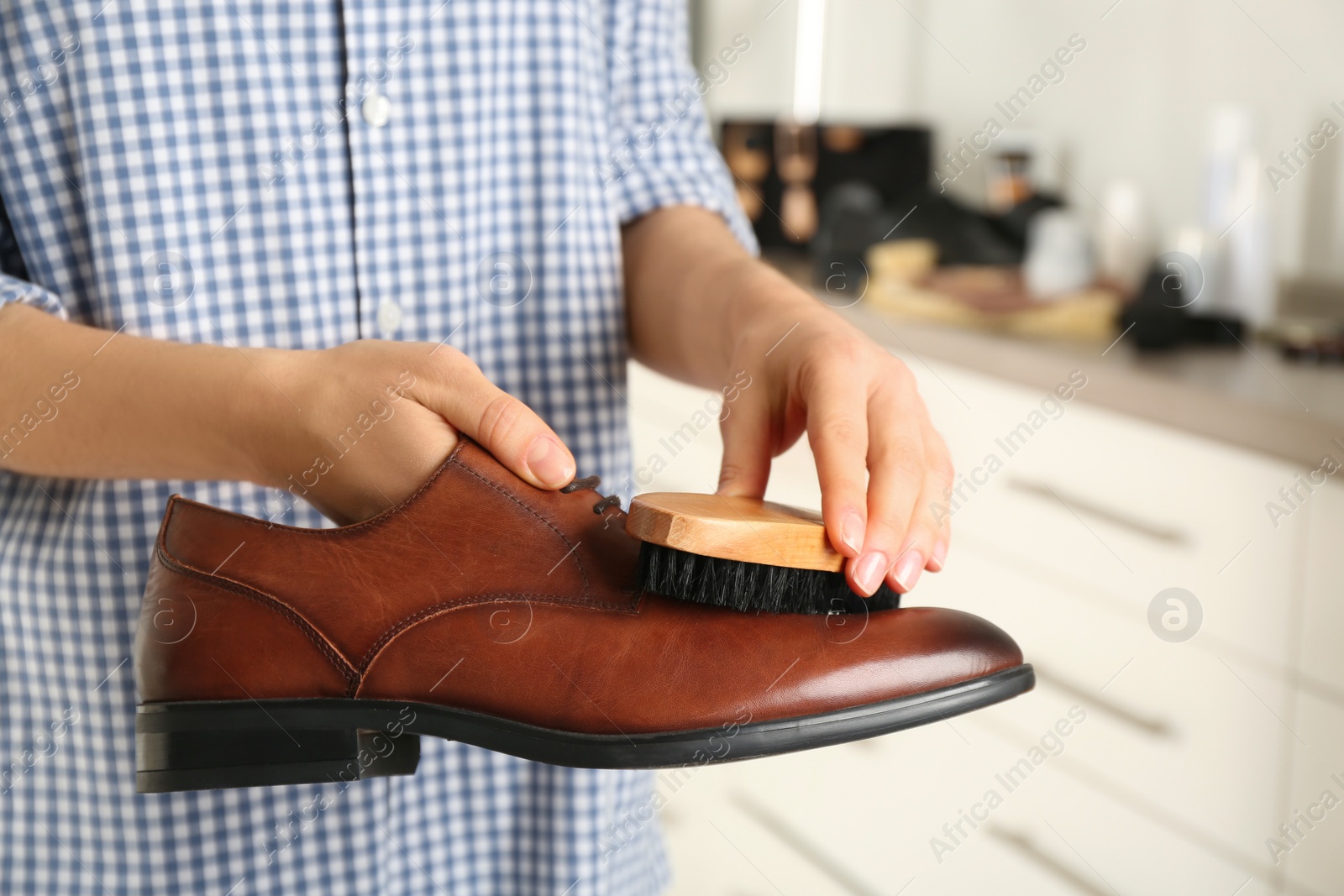 Photo of Woman cleaning stylish footwear indoors, closeup. Shoe care accessories