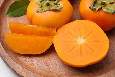 Photo of Delicious ripe persimmons and knife on white table, closeup