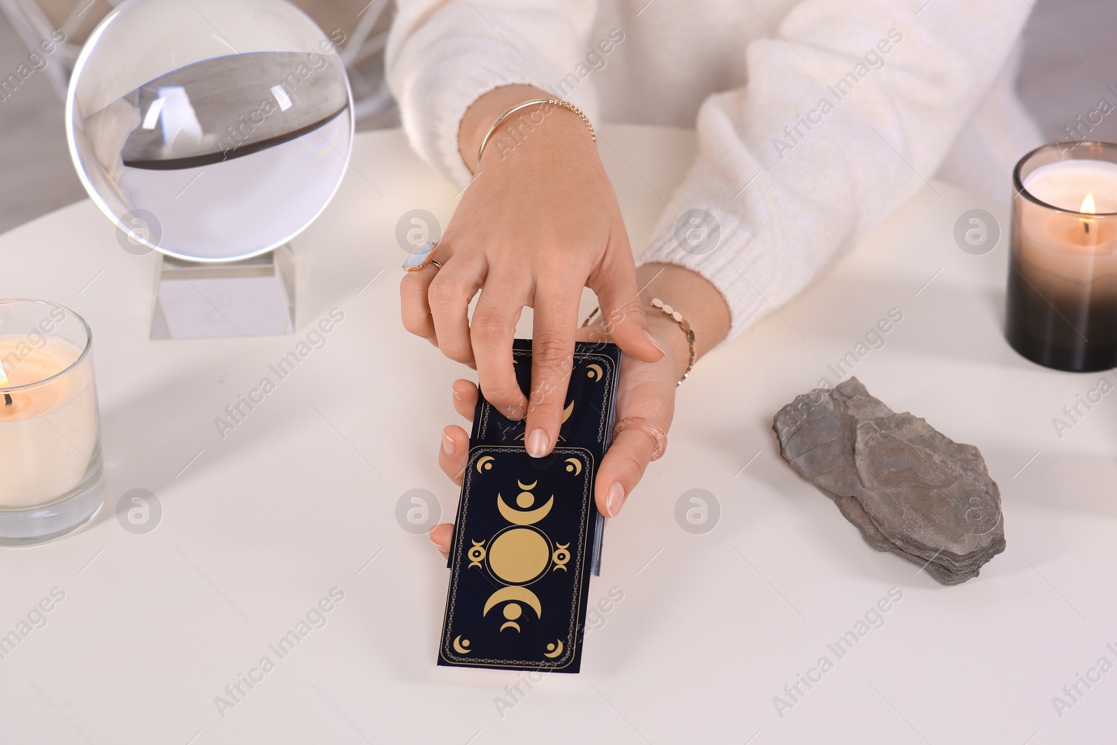 Photo of Soothsayer predicting future with tarot cards at table indoors, closeup