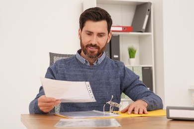 Businessman reading document at wooden table in office