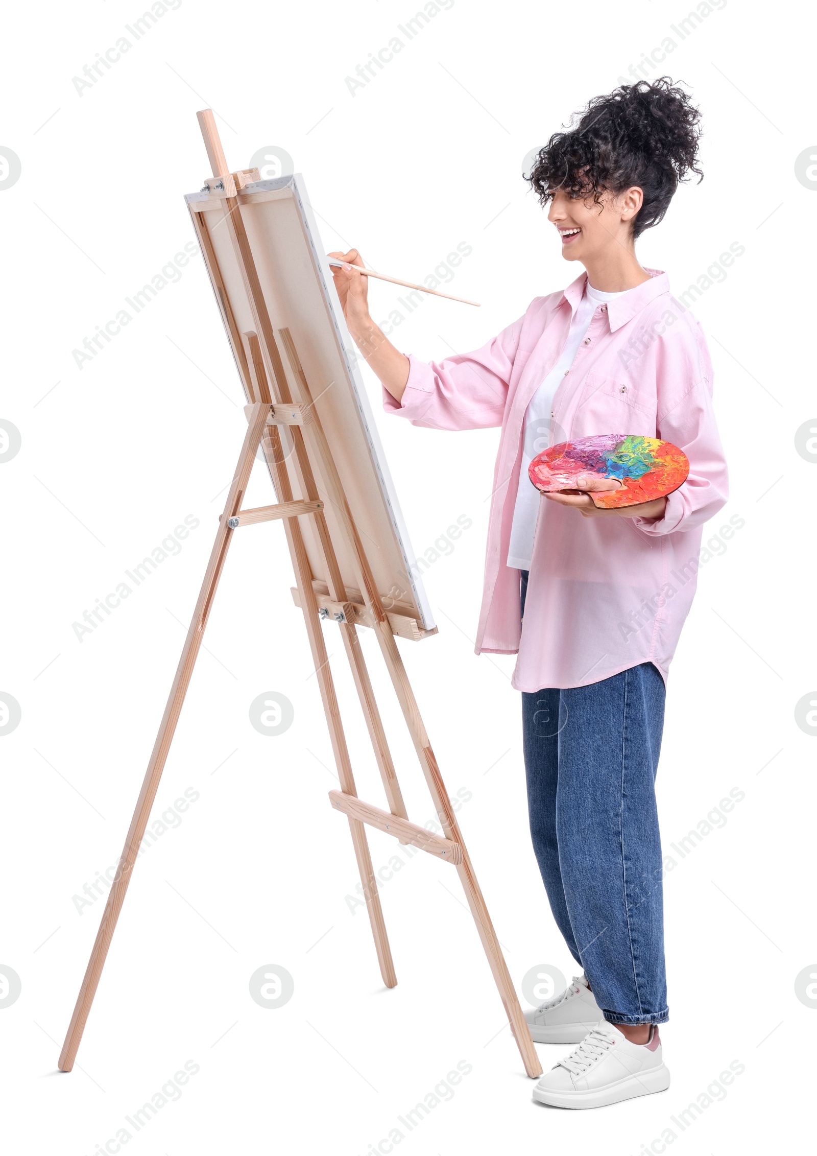 Photo of Young woman painting on easel with canvas against white background