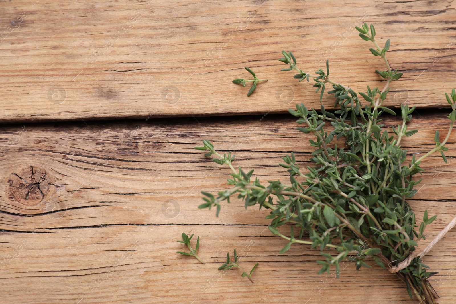 Photo of Bunch of fresh thyme on wooden table, top view. Space for text