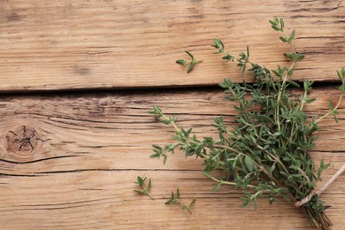 Photo of Bunch of fresh thyme on wooden table, top view. Space for text