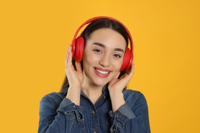 Photo of Portrait of happy woman in headphones listening music on orange background