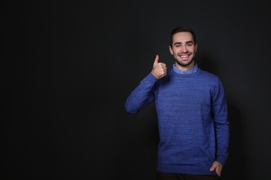 Photo of Man showing THUMB UP gesture in sign language on black background, space for text