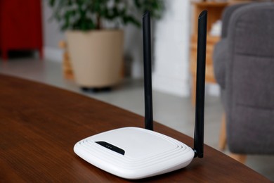 Photo of Modern Wi-Fi router on wooden table indoors. Space for text