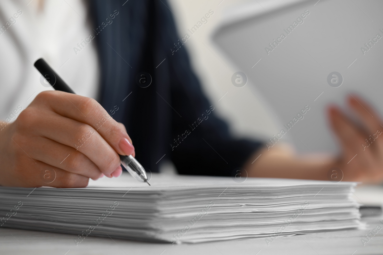 Photo of Woman signing documents at white wooden table in office, closeup. Space for text