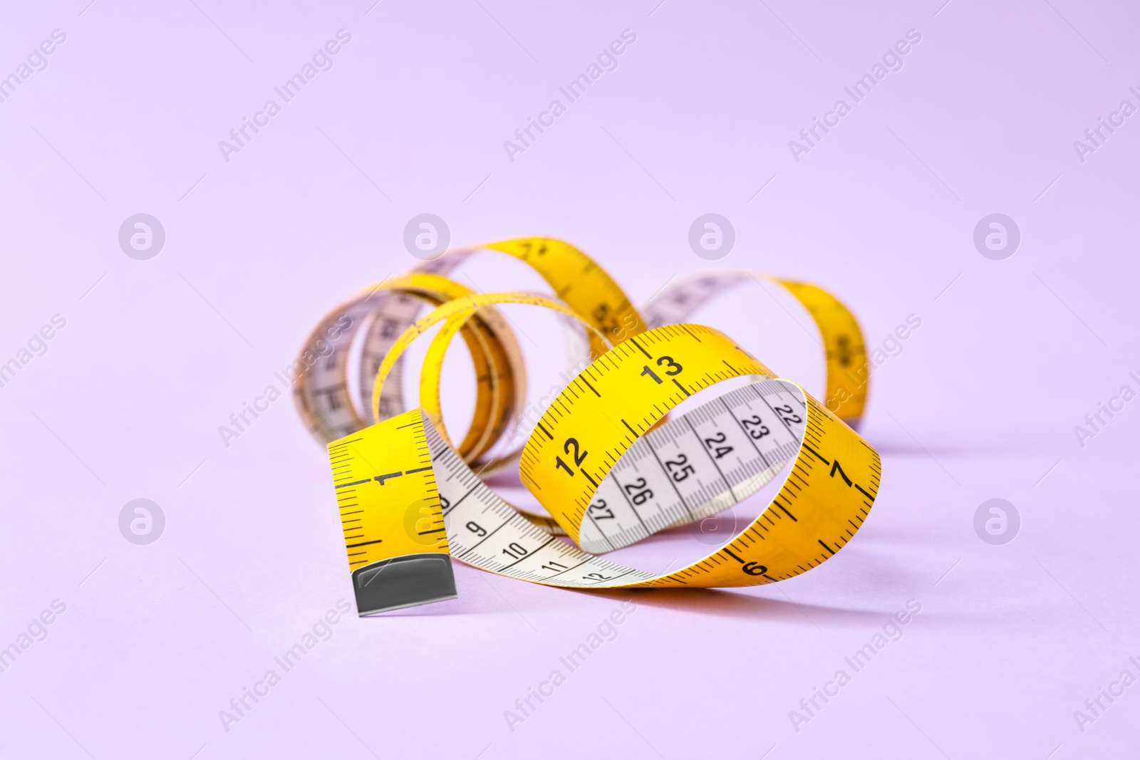 Photo of New measuring tape on violet background, closeup
