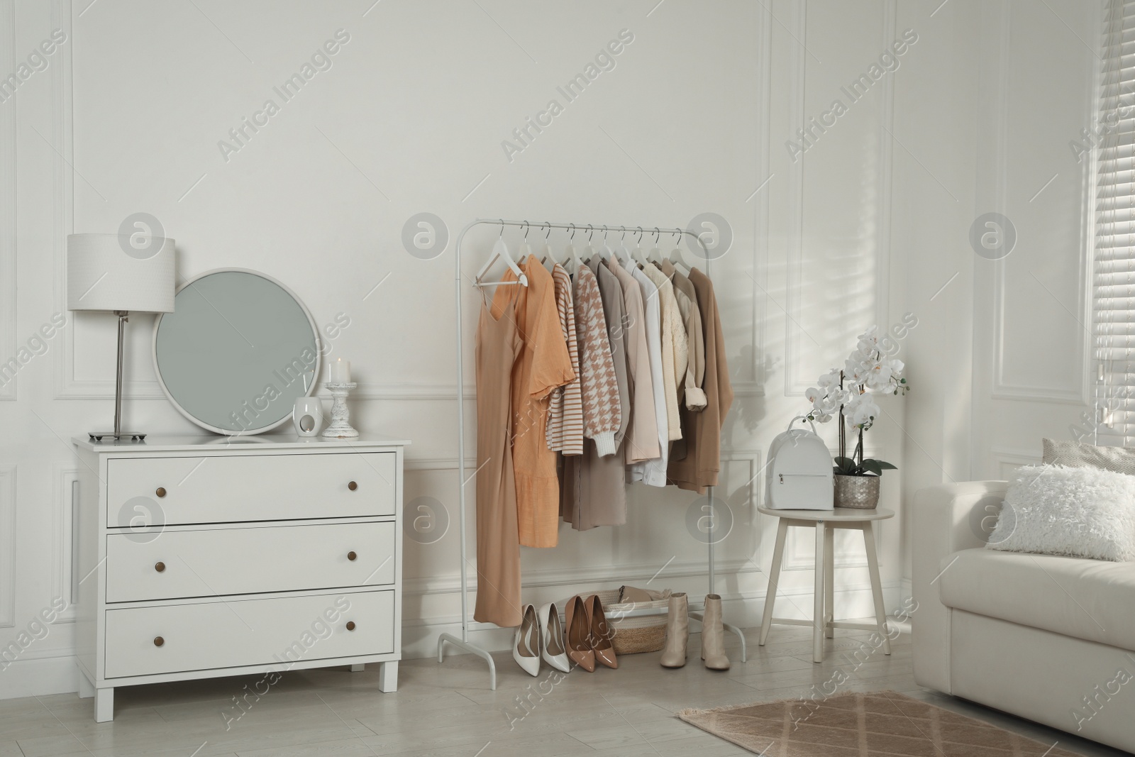 Photo of Modern dressing room interior with stylish clothes, shoes and beautiful orchid flowers