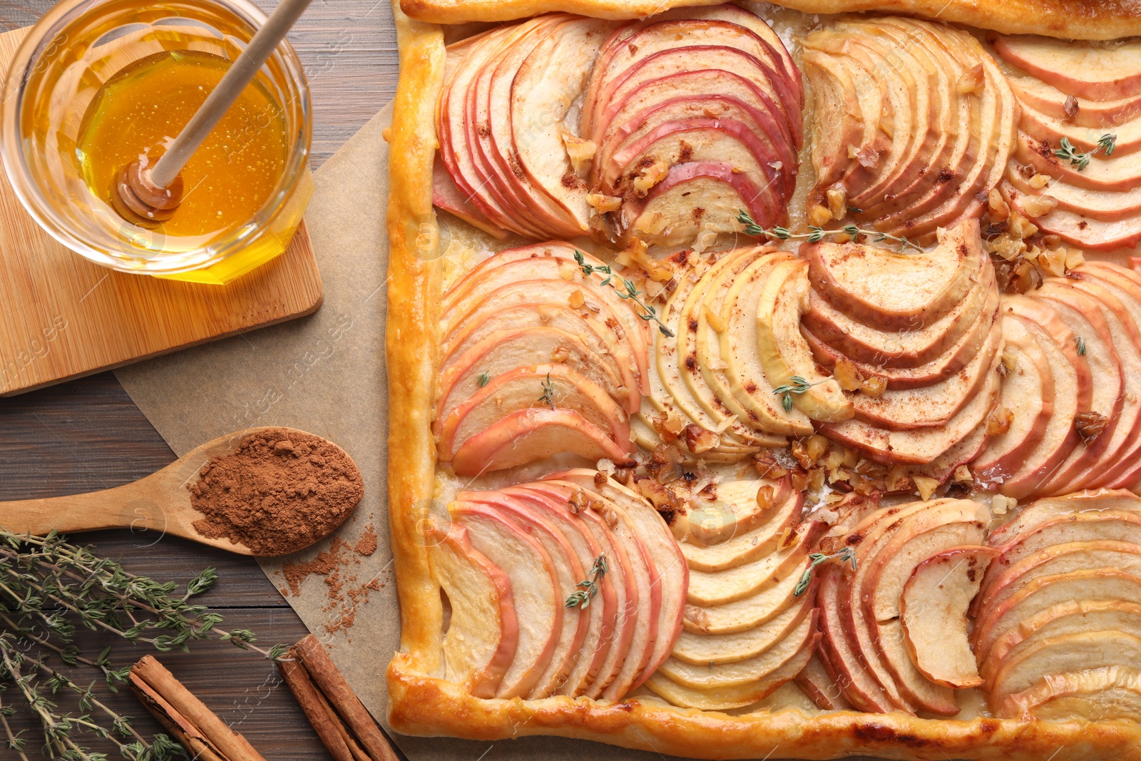 Photo of Freshly baked apple pie with nuts and ingredients on wooden table, flat lay
