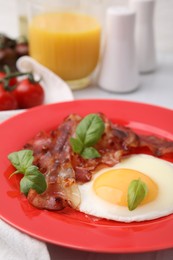 Fried egg, bacon and basil on table