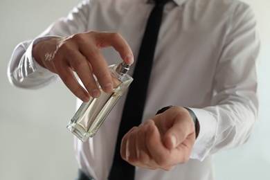 Photo of Man applying perfume on wrist indoors, closeup