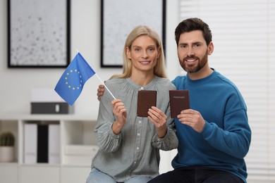 Immigration. Happy couple with passports and flag of European Union indoors