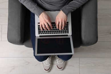 Photo of Man working with laptop in armchair, top view