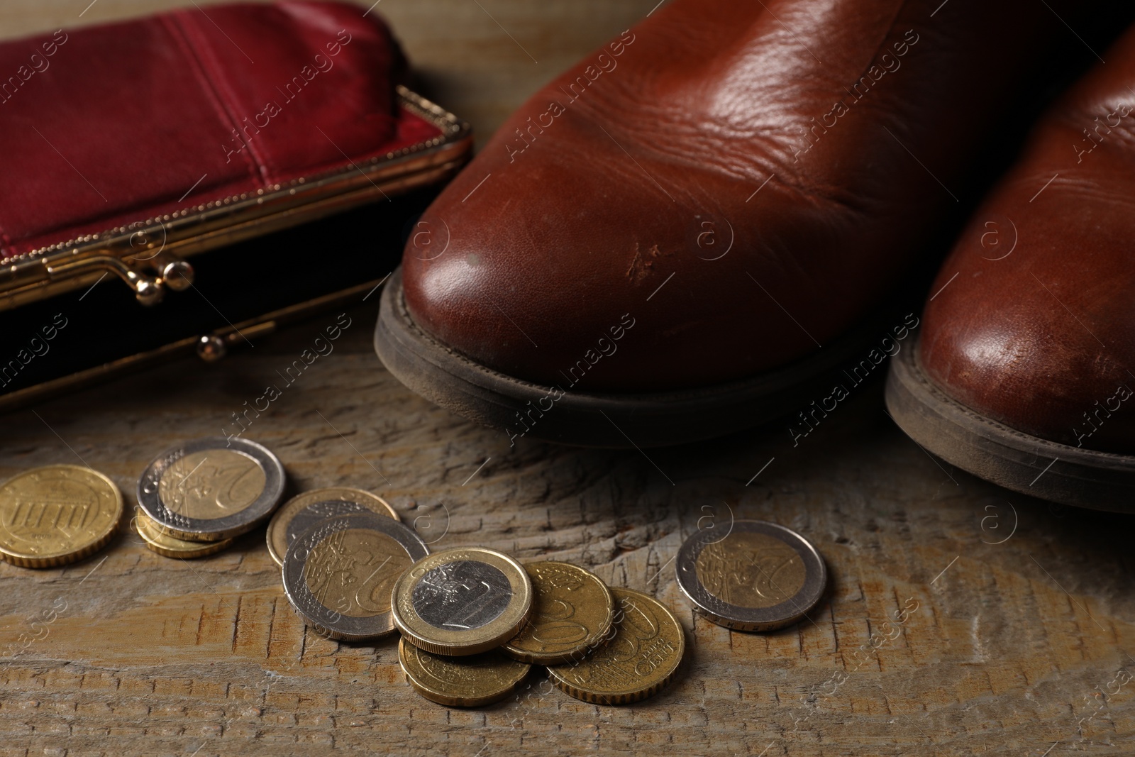 Photo of Poverty. Old boots, wallet and coins on wooden table, closeup