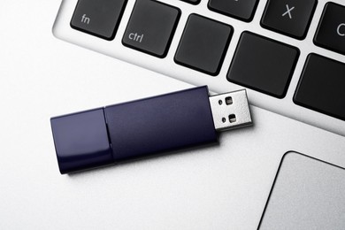 Photo of Modern usb flash drive on laptop, top view