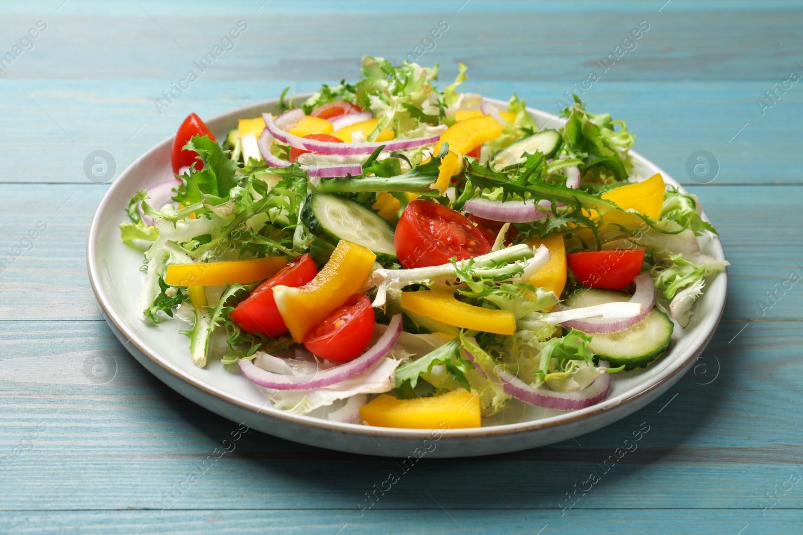 Photo of Tasty fresh vegetarian salad on light blue wooden table, closeup