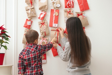 Mother and son taking gift from Advent calendar at home, back view. Christmas tradition