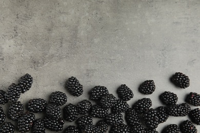 Tasty ripe blackberries on grey table, top view with space for text