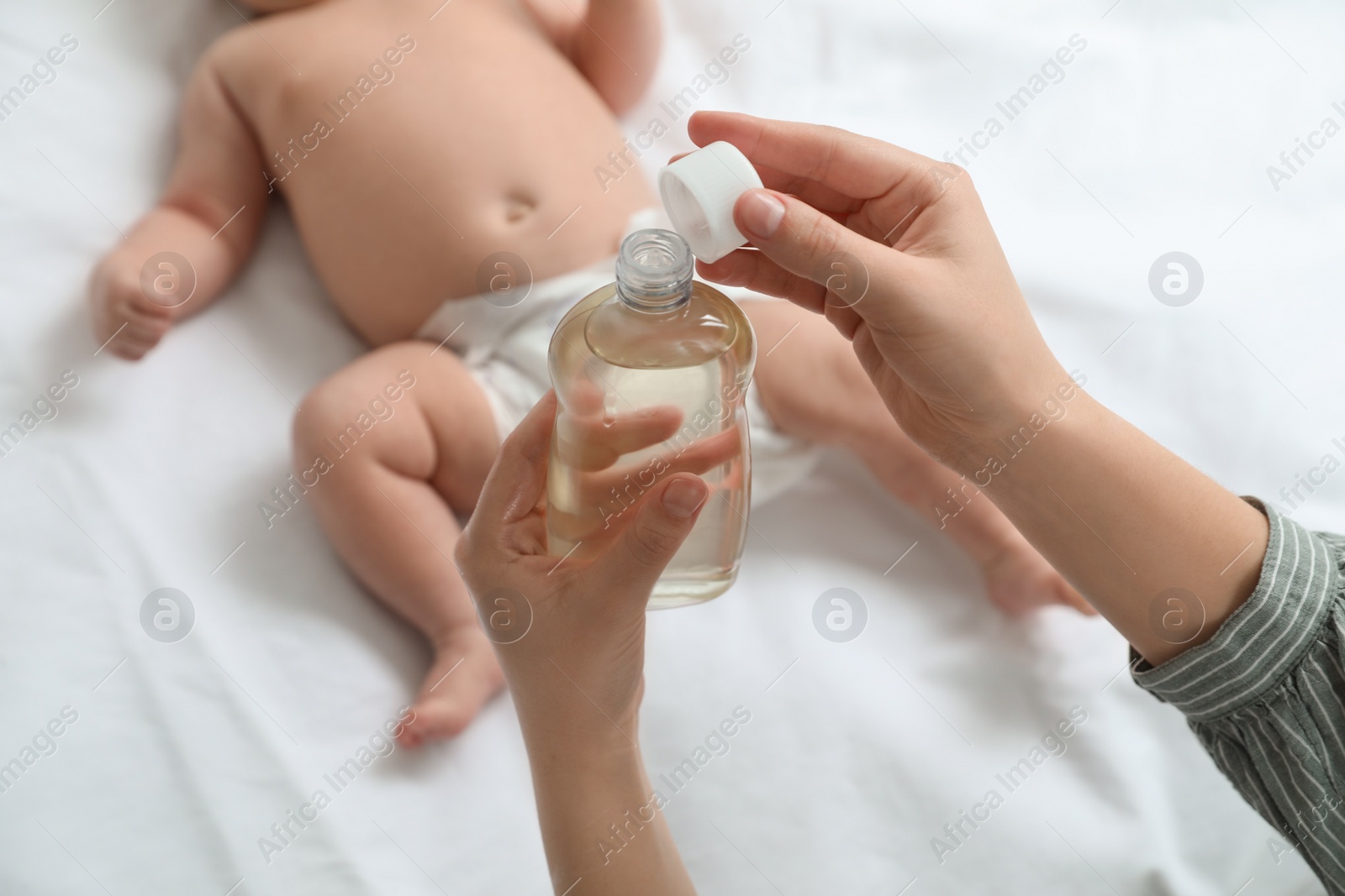 Photo of Mother with massaging oil near her baby, closeup