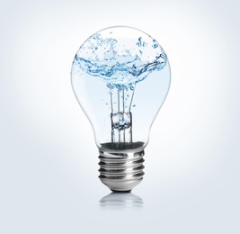 Image of Light bulb with water splashes on light background. Alternative energy source