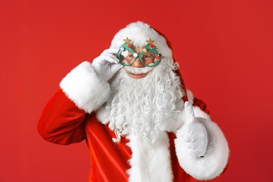 Photo of Authentic Santa Claus wearing funny glasses on color background