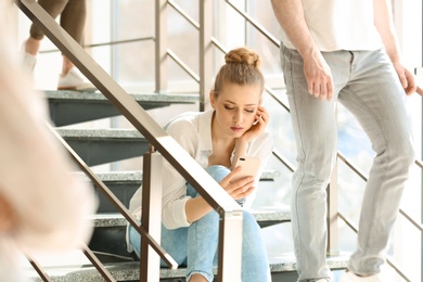 Young woman with smartphone sitting on stairs. Alone among people