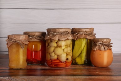Many jars with different preserved ingredients on wooden table