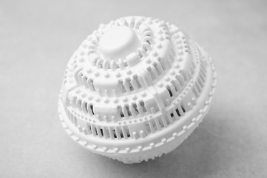 Photo of Dryer ball for washing machine on light grey table, closeup. Laundry detergent substitute