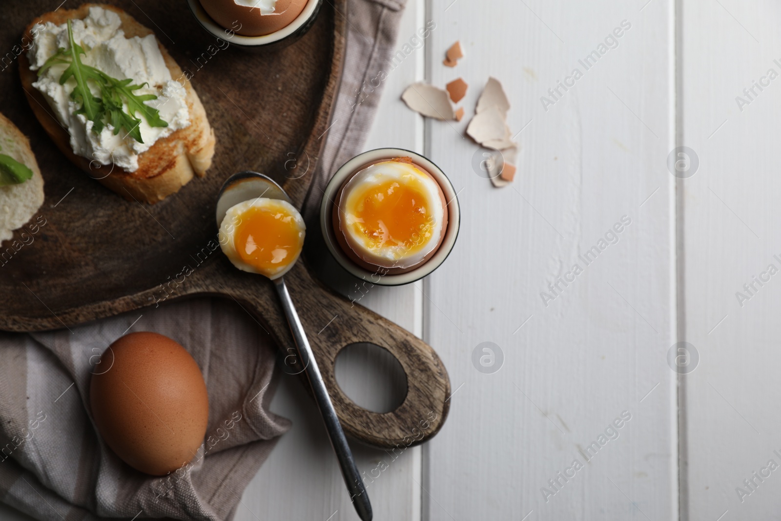 Photo of Breakfast with soft boiled egg served on white wooden table, flat lay. Space for text