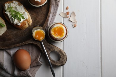 Photo of Breakfast with soft boiled egg served on white wooden table, flat lay. Space for text