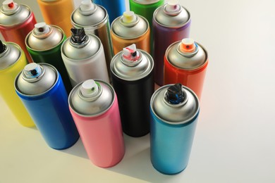 Photo of Cans of different graffiti spray paints on white table