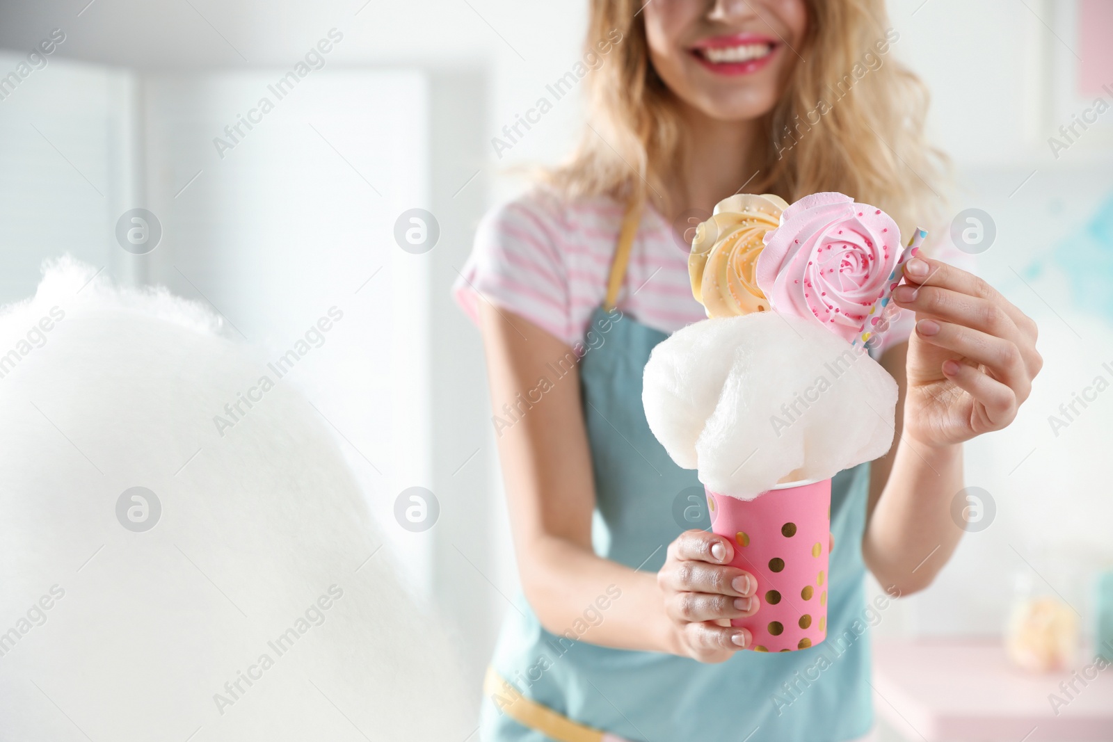 Photo of Young woman with cup of cotton candy dessert indoors, closeup. Space for text