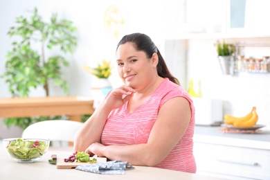 Photo of Overweight woman preparing salad in kitchen. Healthy diet