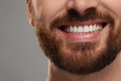 Photo of Smiling man with healthy clean teeth on grey background, closeup