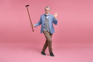 Photo of Senior man with walking cane on pink background