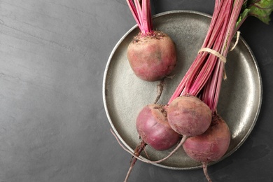 Photo of Raw ripe beets on black slate table, top view. Space for text