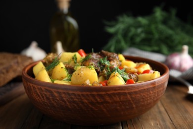 Tasty cooked dish with potatoes in earthenware on wooden table, closeup