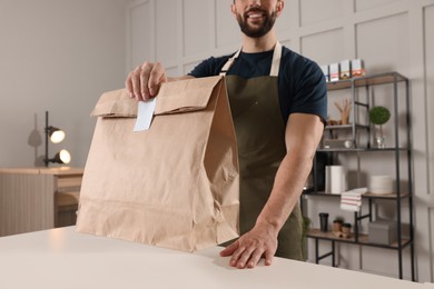 Photo of Worker with paper bag at counter in cafe, closeup