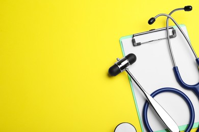 Photo of Reflex hammer, stethoscope and clipboard on yellow background, flat lay with space for text. Nervous system diagnostic