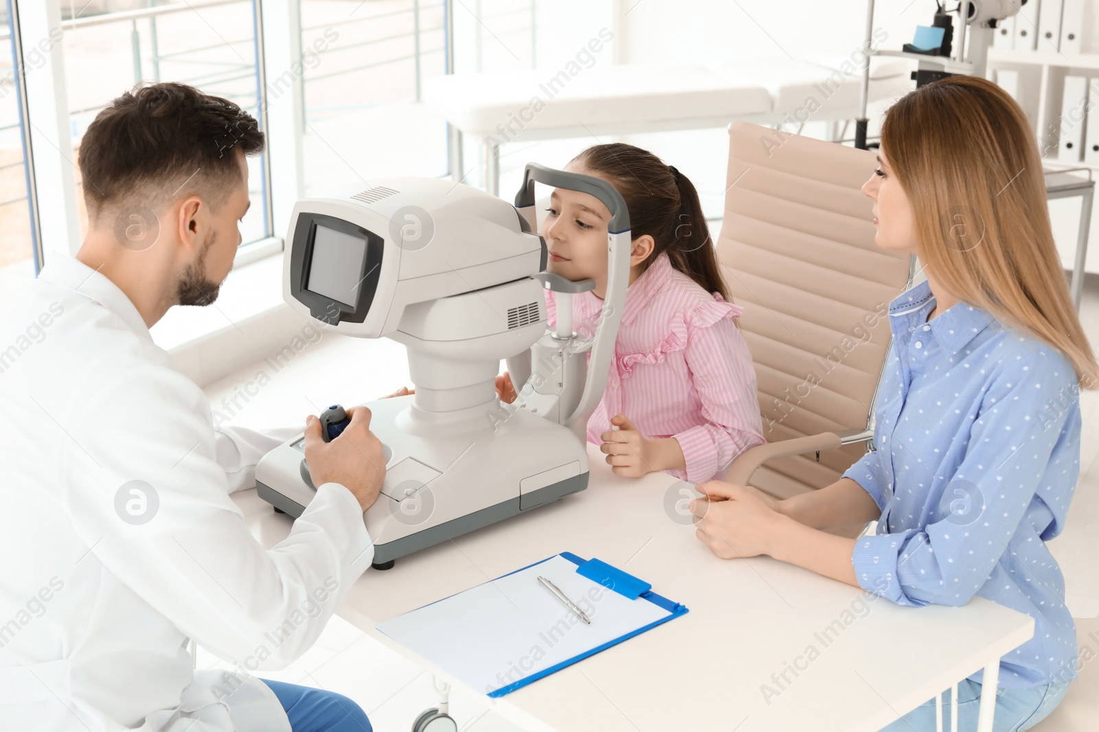 Photo of Little girl with mother visiting ophthalmologist in clinic