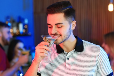 Photo of Young man with glass of martini cocktail at party, space for text