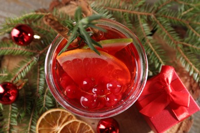 Photo of Aromatic Christmas Sangria in glass, gift box and festive decor on table, top view