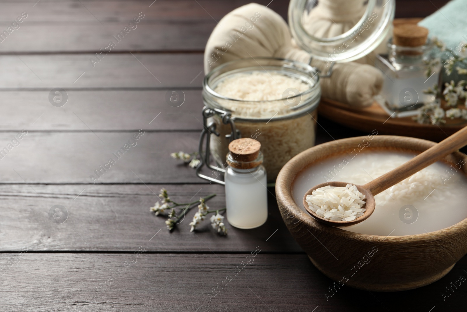 Photo of Bowl with soaked rice and spoon on wooden table. Space for text